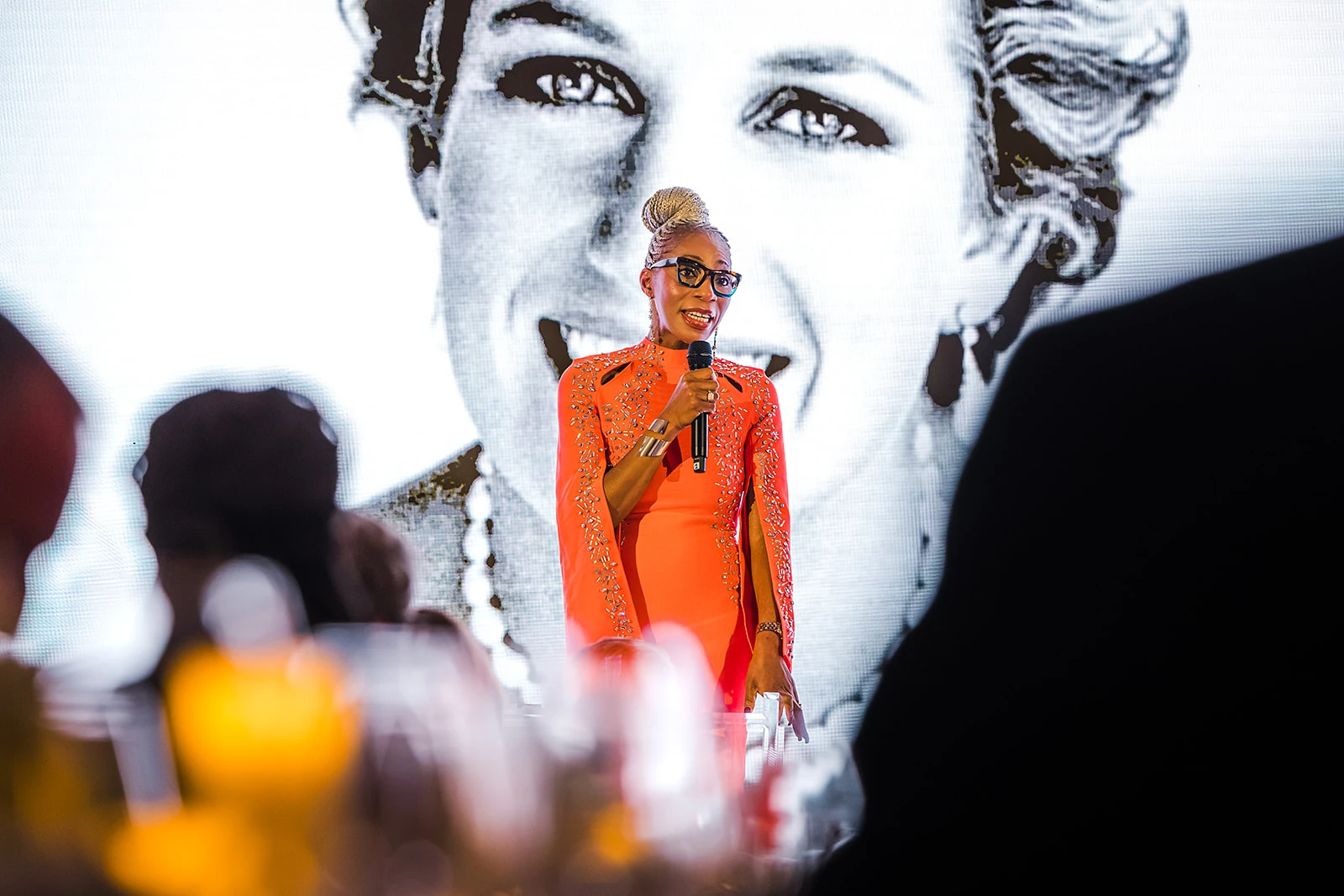 Dr Tessy Ojo CBE speaking at The 64, with a portrait of Diana behind her